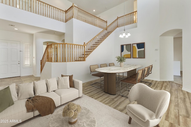 living area featuring arched walkways, stairs, light wood-style flooring, and a notable chandelier