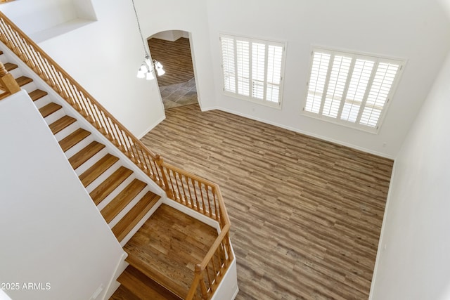 stairway featuring a notable chandelier, baseboards, and wood finished floors