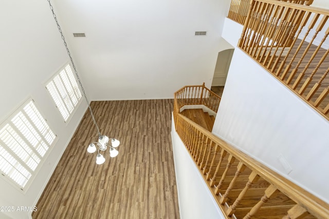 stairs with a towering ceiling, visible vents, and a notable chandelier