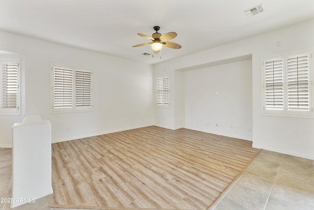 spare room featuring light wood finished floors, baseboards, visible vents, and a ceiling fan