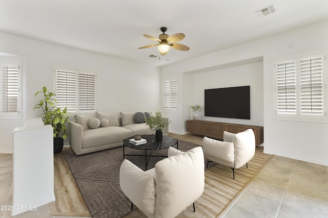 living room featuring baseboards, visible vents, and a ceiling fan