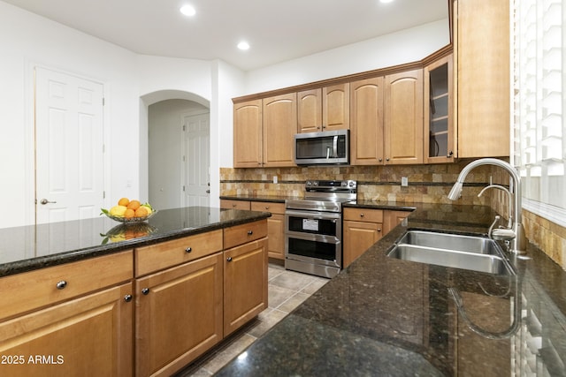 kitchen featuring stainless steel appliances, recessed lighting, backsplash, glass insert cabinets, and a sink