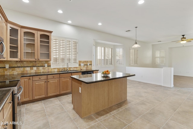 kitchen featuring stainless steel appliances, a sink, decorative backsplash, dark stone counters, and glass insert cabinets