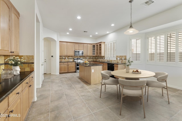 kitchen with arched walkways, decorative light fixtures, visible vents, appliances with stainless steel finishes, and glass insert cabinets