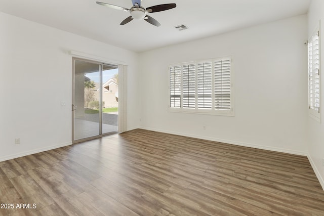 unfurnished room featuring a ceiling fan, wood finished floors, visible vents, and baseboards