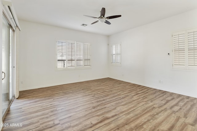 spare room featuring baseboards, a ceiling fan, visible vents, and light wood-style floors