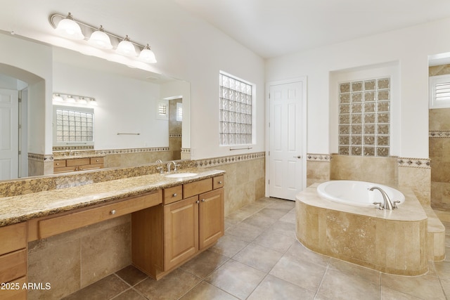 bathroom featuring a wainscoted wall, vanity, tile walls, a bath, and tile patterned floors