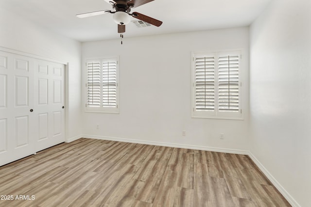 unfurnished bedroom featuring light wood-type flooring, a closet, visible vents, and baseboards