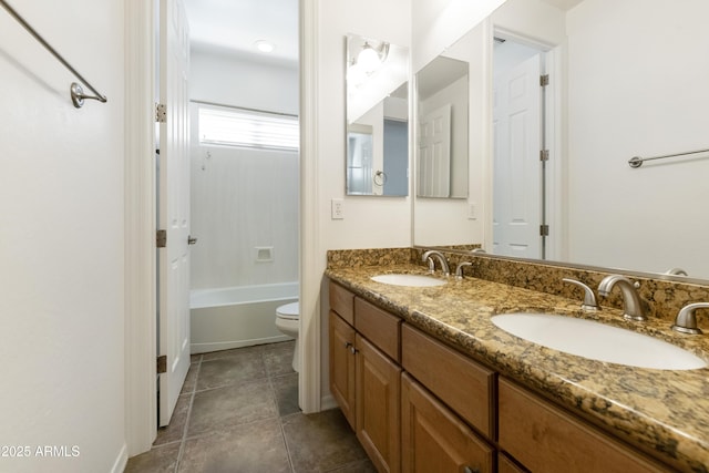 full bath with toilet, double vanity, a sink, and tile patterned floors