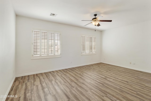 spare room featuring light wood-style floors, visible vents, ceiling fan, and baseboards