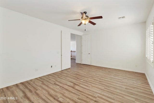 unfurnished room featuring a ceiling fan, light wood-type flooring, visible vents, and baseboards