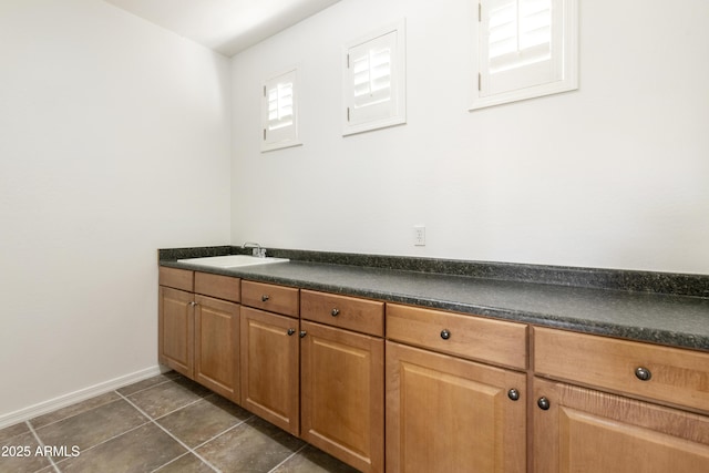 bathroom featuring baseboards, a sink, and tile patterned floors