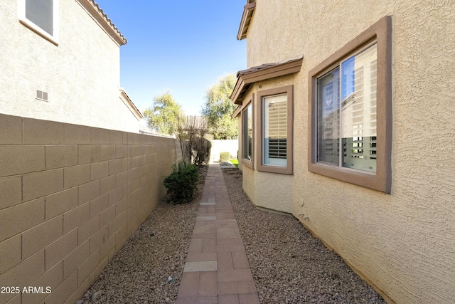 view of home's exterior with a fenced backyard, a tiled roof, and stucco siding