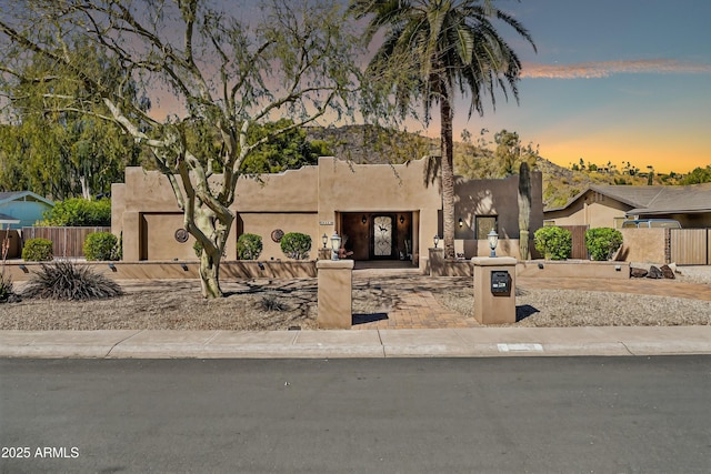 pueblo-style home with fence