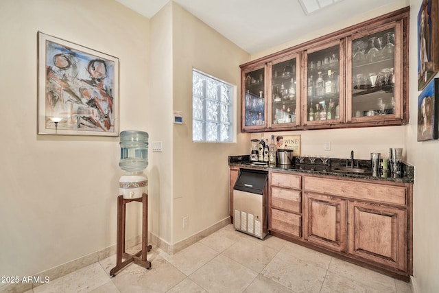 bar featuring a sink, indoor wet bar, baseboards, and light tile patterned flooring