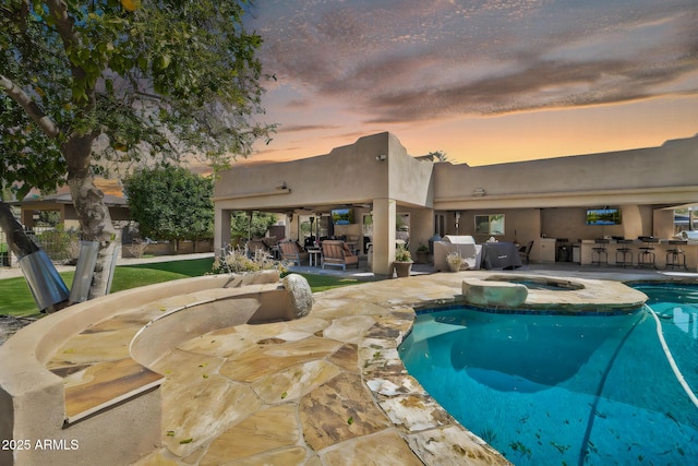 view of pool featuring a patio area, an outdoor kitchen, a pool with connected hot tub, and outdoor dry bar