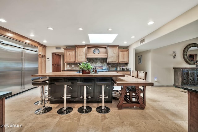 kitchen featuring visible vents, built in refrigerator, backsplash, recessed lighting, and custom exhaust hood