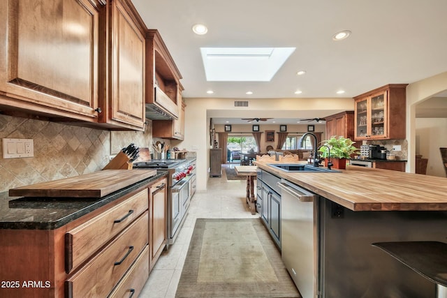 kitchen with visible vents, a sink, stainless steel appliances, a skylight, and butcher block counters