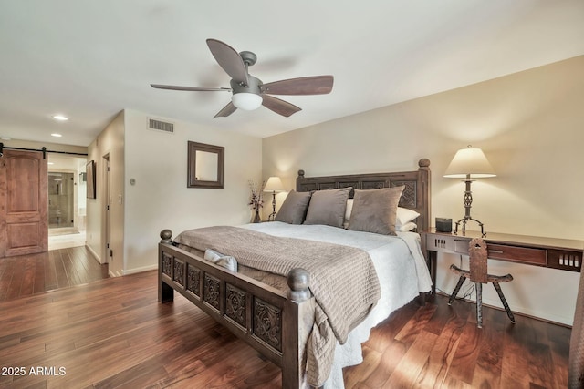 bedroom featuring wood finished floors, visible vents, baseboards, recessed lighting, and a barn door