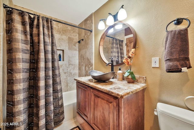 bathroom with vanity, toilet, shower / tub combo with curtain, and a textured wall