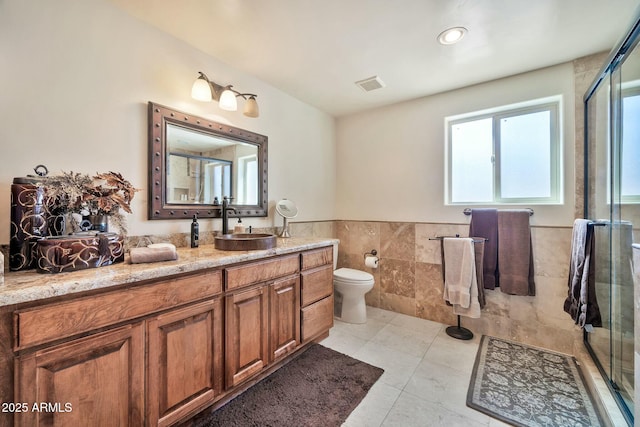 full bathroom featuring vanity, tile patterned flooring, a shower stall, tile walls, and toilet