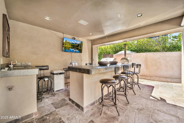 view of patio with an outdoor kitchen, outdoor wet bar, and a sink