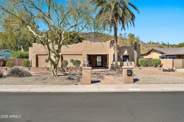 pueblo revival-style home featuring a mountain view and fence