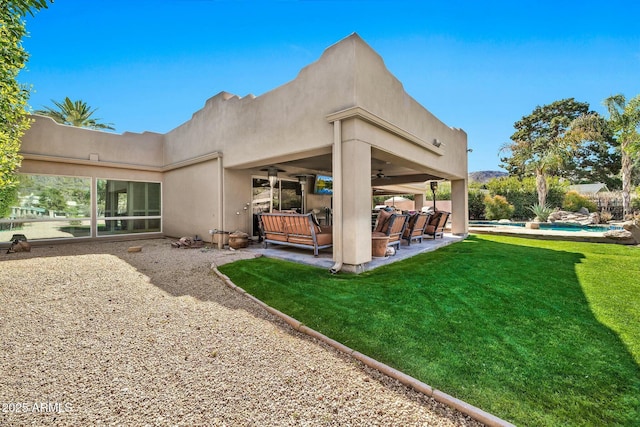 back of property featuring a fenced in pool, ceiling fan, stucco siding, a yard, and a patio area