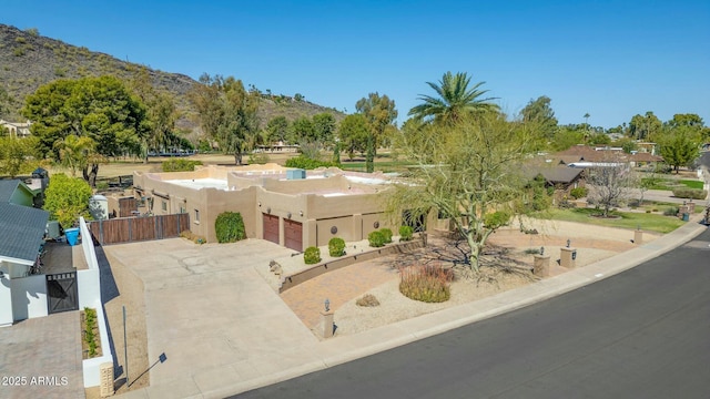 view of front of home featuring stucco siding, driveway, fence, a mountain view, and a garage