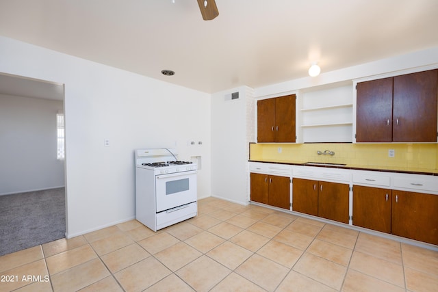 kitchen with light tile patterned floors, ceiling fan, decorative backsplash, sink, and white range with gas stovetop