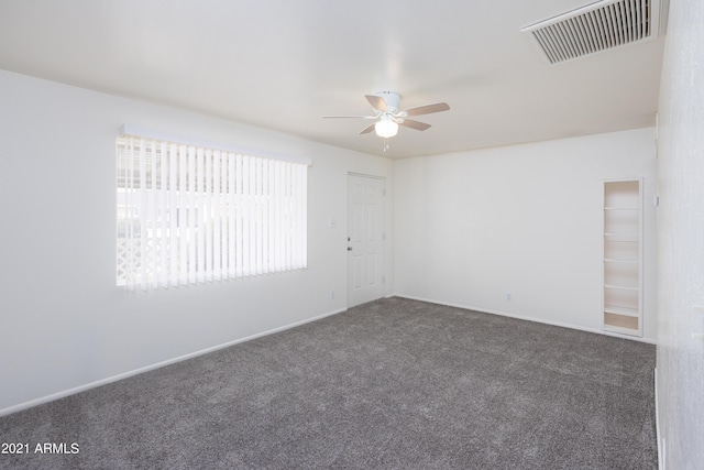 unfurnished room with ceiling fan and dark carpet