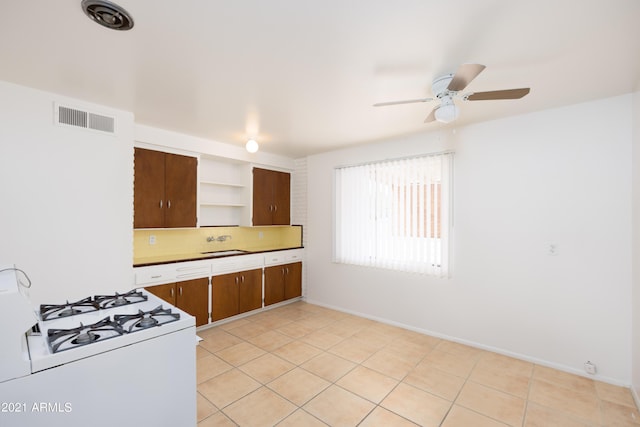 kitchen featuring light tile patterned floors, ceiling fan, white gas range oven, decorative backsplash, and sink