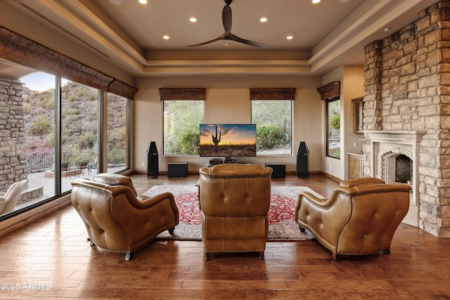 11550 E Paradise Ln, Scottsdale, AZ 85255 - living room featuring a tray ceiling, wood-type flooring, a stone fireplace, a ceiling fan, and recessed lighting