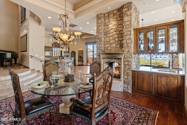 11550 E Paradise Ln, Scottsdale, AZ 85255 - dining room featuring arched walkways, a chandelier, recessed lighting, dark wood-style flooring, and a stone fireplace