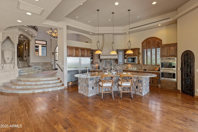 11550 E Paradise Ln, Scottsdale, AZ 85255 - kitchen featuring built in appliances, a spacious island, tasteful backsplash, dark wood-style floors, and a breakfast bar