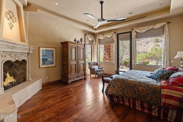 11550 E Paradise Ln, Scottsdale, AZ 85255 - bedroom featuring a raised ceiling, baseboards, hardwood / wood-style flooring, a premium fireplace, and access to outside