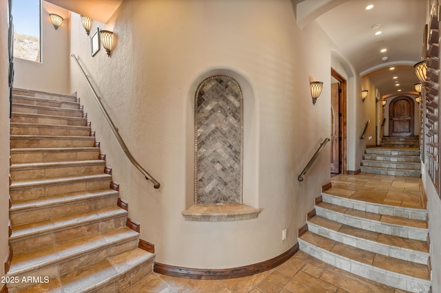 11550 E Paradise Ln, Scottsdale, AZ 85255 - staircase with recessed lighting, arched walkways, stone tile flooring, baseboards, and lofted ceiling