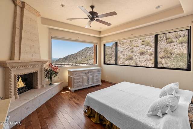 11550 E Paradise Ln, Scottsdale, AZ 85255 - bedroom with a mountain view, dark wood-style flooring, a premium fireplace, and a ceiling fan