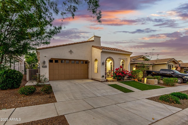 20784 W Minnezona Ave, Buckeye, AZ 85396 - mediterranean / spanish house featuring driveway, a tiled roof, stucco siding, and an attached garage