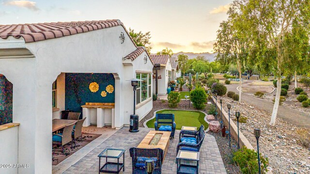 20784 W Minnezona Ave, Buckeye, AZ 85396 - patio terrace at dusk featuring an area to practice putting, a patio, and outdoor dining space