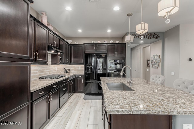 20784 W Minnezona Ave, Buckeye, AZ 85396 - kitchen with black appliances, a sink, under cabinet range hood, an island with sink, and tasteful backsplash