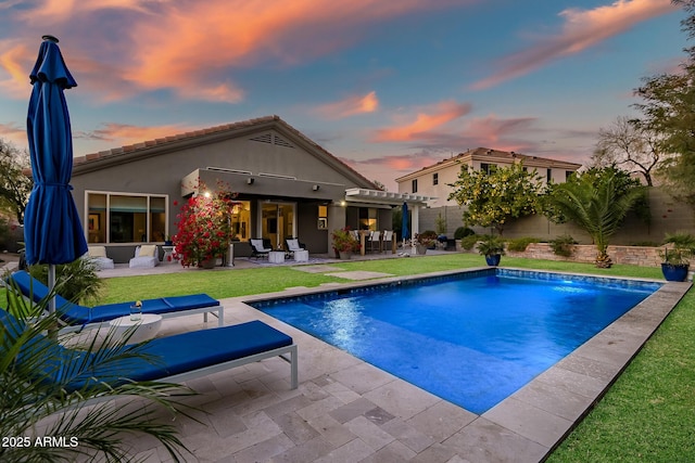 pool at dusk featuring a patio, a pergola, an outdoor hangout area, and a lawn