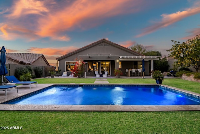 pool at dusk with a yard and a patio area