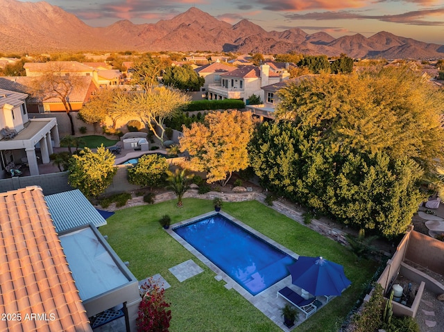 pool at dusk with a mountain view and a lawn