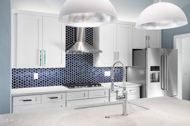 kitchen with stainless steel appliances, wall chimney exhaust hood, white cabinets, and decorative backsplash