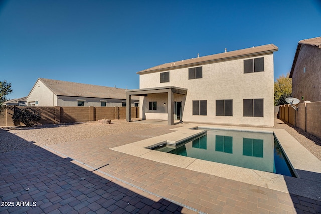 back of property with a patio area and a fenced in pool