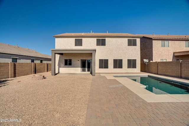 rear view of property featuring a patio area and a fenced in pool