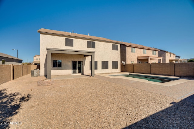 back of property featuring central air condition unit, a patio area, and a fenced in pool