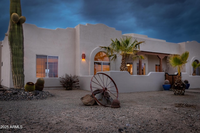 adobe home with a fenced front yard and stucco siding