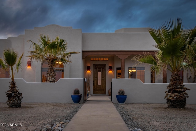 view of front facade with a fenced front yard, a gate, and stucco siding